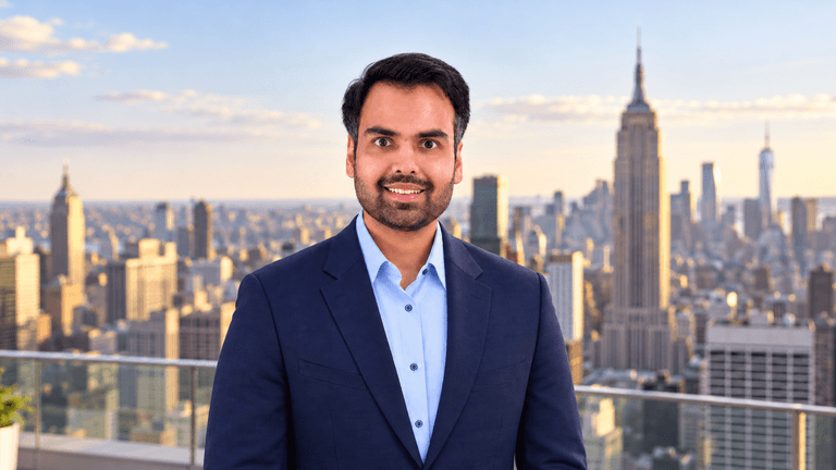 A man in a suit stands with a city skyline backdrop featuring skyscrapers