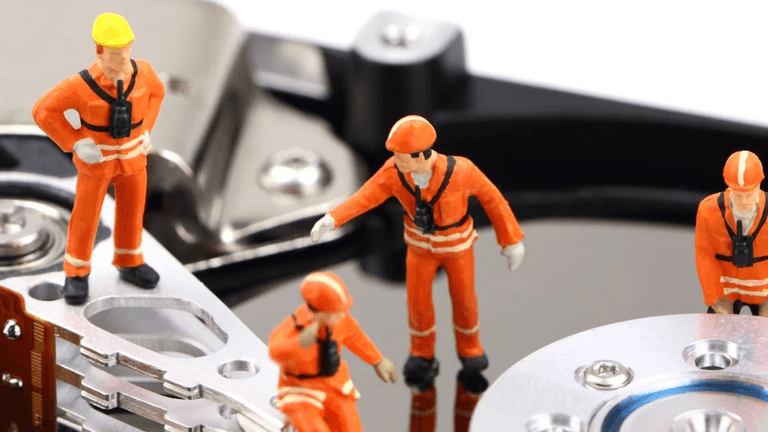"Miniature construction workers on a hard drive, symbolizing Kelley Information Technology’s hands-on, personalized IT support for small businesses."