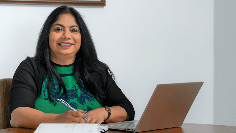 "Chamila Udagedara, CEO of Capital Legal Solicitors, providing compassionate, integrity-driven legal services while working confidently at her desk with a laptop."