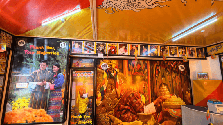Close-up of Ola Tours’ “Thank You, Your Majestics” poster with a Bhutanese couple.
