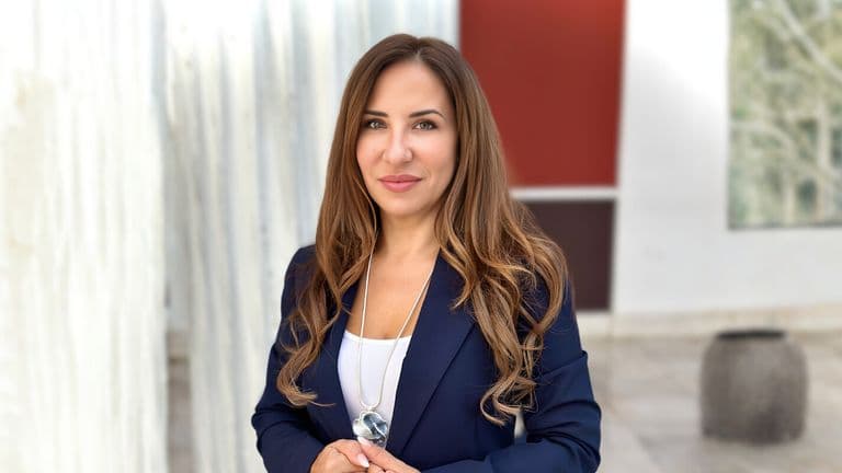Dr. Barbara Geladakis, founder of RODI Fertility, standing confidently in a navy suit, with a professional expression.