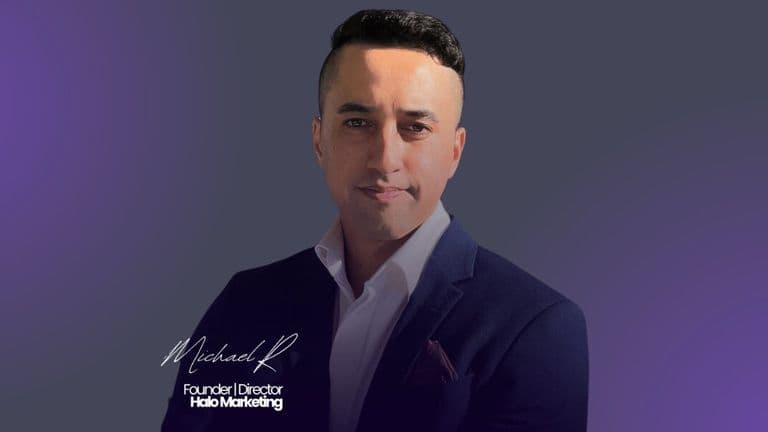 Michael Ripia in a suit and tie stands confidently against a vibrant purple background.