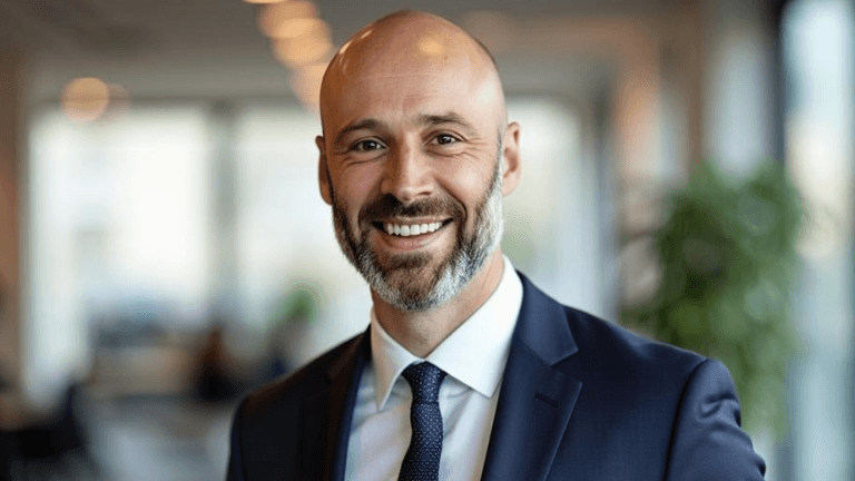 Smiling business professional in a suit representing Cochran Capital’s founder, promoting sustainable real estate investment.