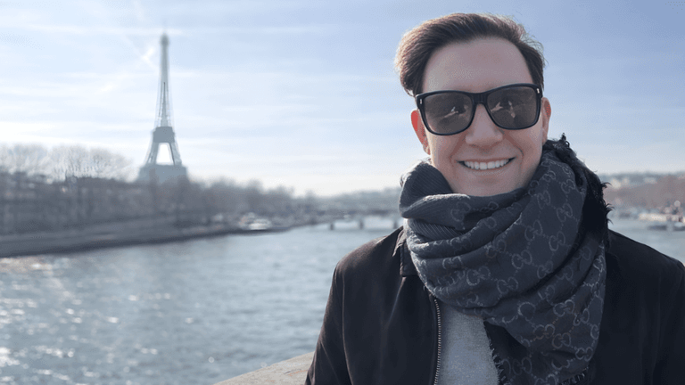 Zach Randles-Friedman smiling with the Eiffel Tower in the background during a visit to Paris.