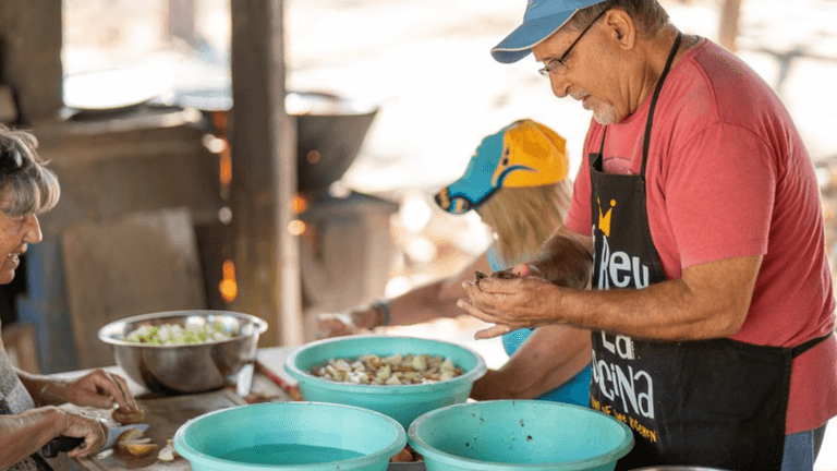 Volunteers preparing food together in an outdoor kitchen at The Monkey Farm community project.