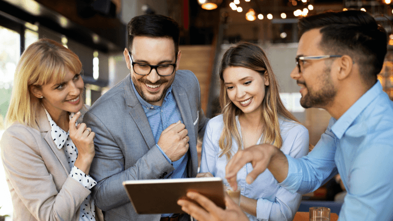 Four professionals discussing ideas, collaborating in a modern office space, embodying global communication and teamwork for growth.