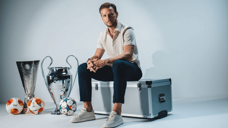 Footballer sits beside Champions League and Europa League trophies, representing EXCENSY Group’s legacy-driven athlete representation.