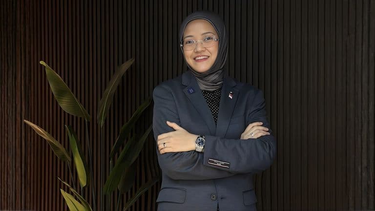 Miss Miza Abdul Halek, founder of Bespoke Capital, standing confidently with arms crossed, wearing a professional suit.