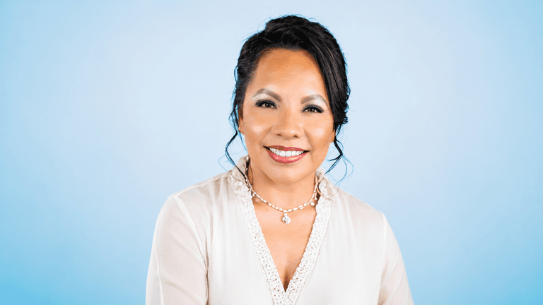 Dr. Maricela Soberanes smiling in a white blouse against a blue background.