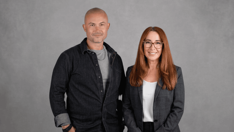 Tyler Pereversoff and Rhian Lois Wight standing together against a gray studio background.