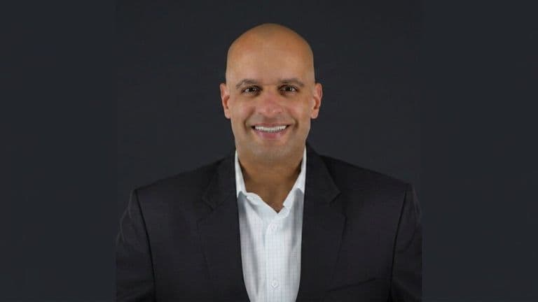 Portrait of Decision Point author Micah Maxwell wearing a dark blazer against a dark background.