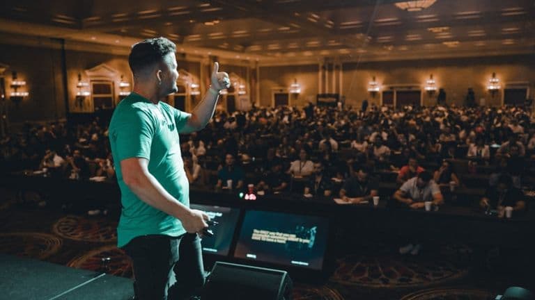 Chris Lee speaking to a large audience at a business event, sharing insights on scaling businesses and leadership.