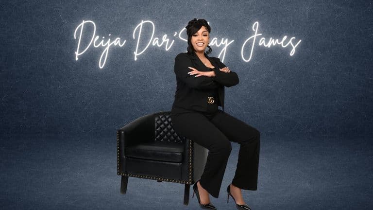 Deija Dar’Shay James seated in black business attire before a branded backdrop, representing entrepreneurship and business leadership.