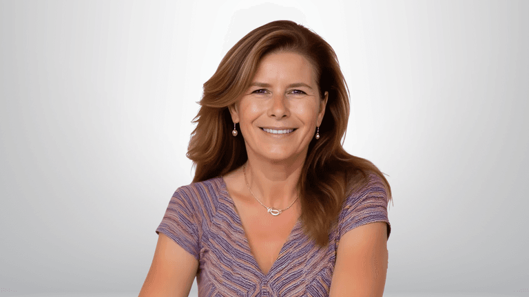 Professional portrait of a smiling woman with shoulder-length brown hair, wearing a purple top and gold earrings, with a soft gradient background.