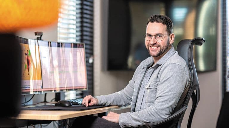 Smiling Ecomtrada founder Lennard Steeman working at dual monitors in an office, illustrating ecommerce Google Ads expertise.