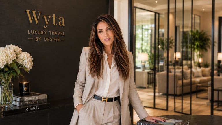 Woman standing in elegant luxury travel office beneath “Wyta Luxury Travel by Design” sign.