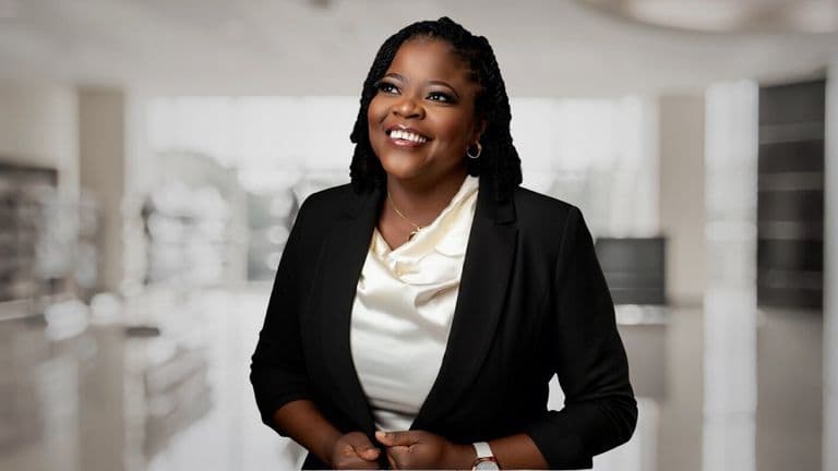 A smiling woman in a business suit, representing innovation in creative technology and entrepreneurship.