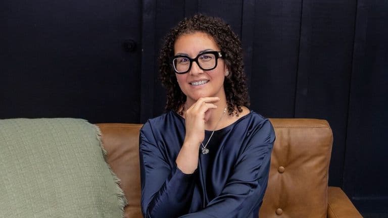 Gina Reyes seated on a sofa, smiling, featured in article about mortgage lending and underwriting expertise.