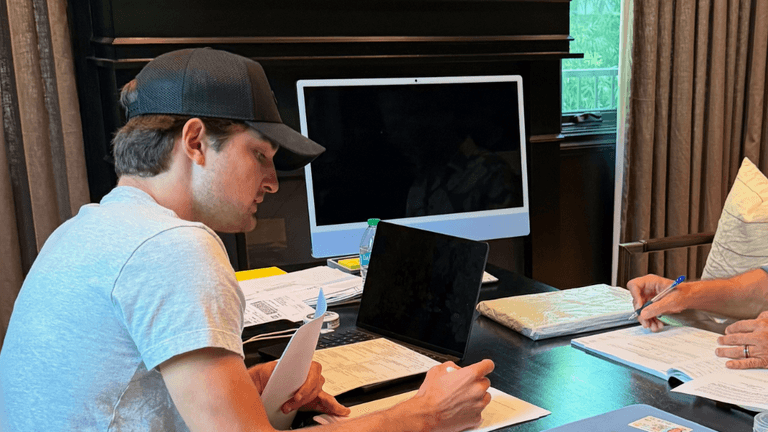 Preston Landes, founder of PL Capital, working with a colleague at a desk, reviewing documents and business plans. The image reflects his hands-on approach to real estate investment and his commitment to mentoring new investors while scaling his business.