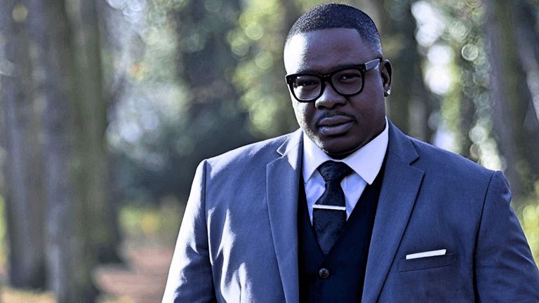 Freddy Will, CEO of Badson Publishing, stands confidently in a suit, embodying his global influence in music and literature.