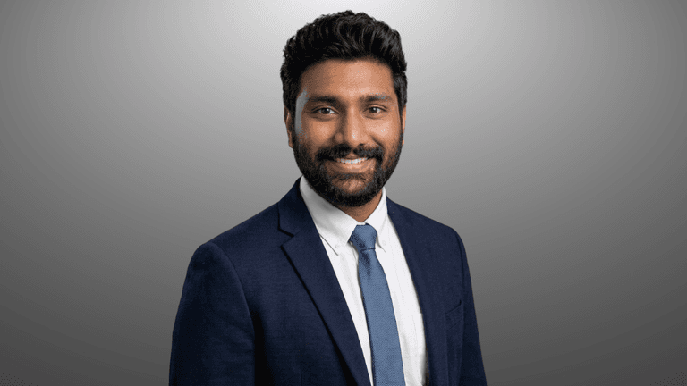 Duvvuru Sravan Kumar Reddy in a gray suit and white shirt against a gray background.