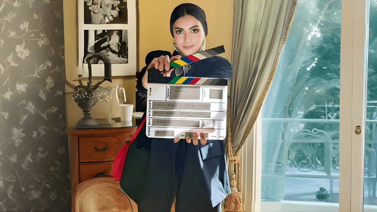Jamila Sangaré, founder of Iconic Frame Productions, holding a film clapperboard, symbolizing her leadership in cross-cultural cinema.