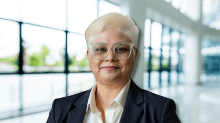 Dr. Alice Preetha in a business suit, smiling confidently inside a bright, modern office building.