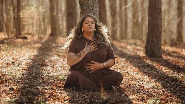 Tiffany Marshall meditating in a forest, embodying the AUM Method™'s Fall phase of release and inner peace.