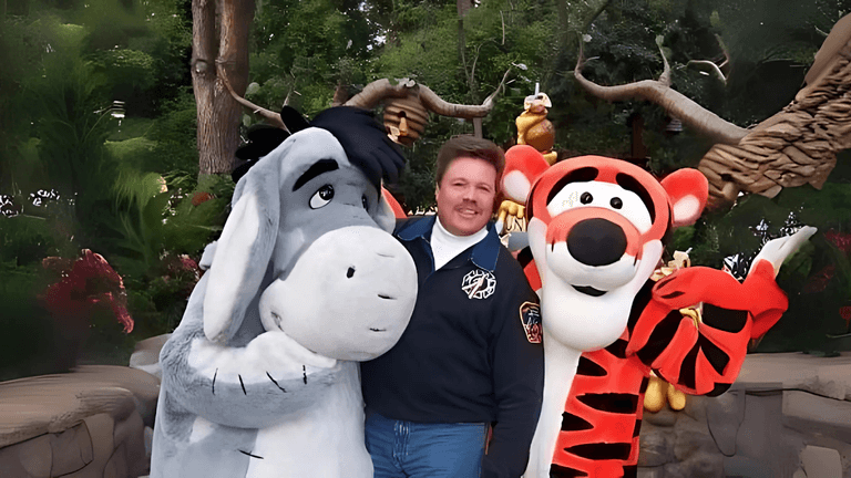 A man posing with Disney characters Eeyore and Tigger at a theme park, symbolizing the creative freedom and community-building spirit of GB-K Productions, a platform supporting independent artists in film, music, and other artistic industries.