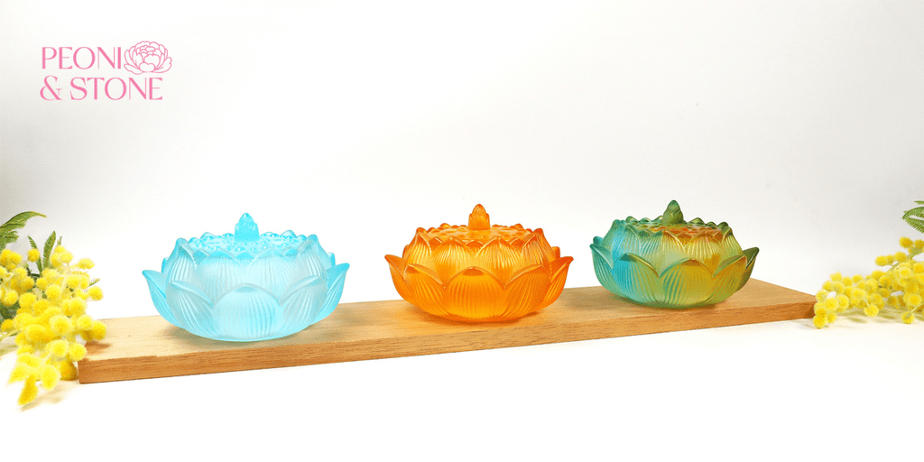 Colorful lotus-shaped incense burners displayed on a wooden shelf with flowers and Peoni & Stone branding.