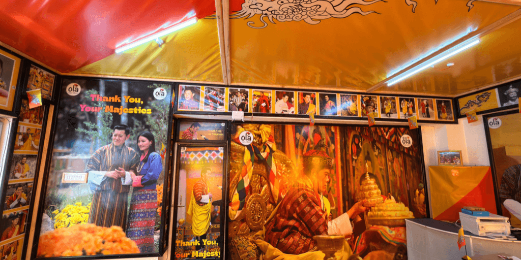 Close-up of Ola Tours’ “Thank You, Your Majestics” poster with a Bhutanese couple.