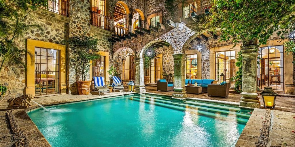 Luxury courtyard home with swimming pool, stone arches, and colonial architecture in San Miguel de Allende at night.
