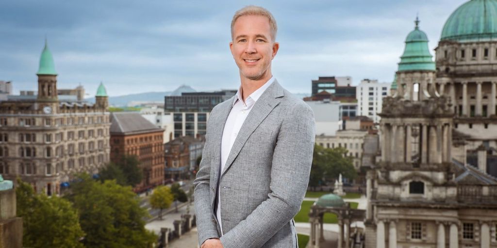 Ray Gilmour, CEO of MarketsMadeClear.com, stands confidently with the Belfast skyline behind him, symbolizing clarity in trading.