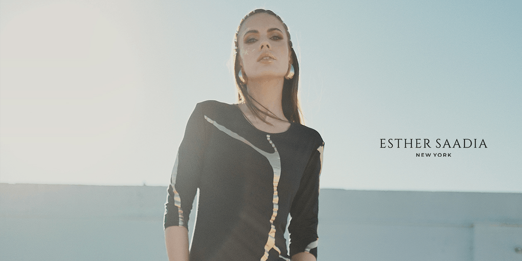 Elegant woman wearing a black modest dress with metallic accents, photographed outdoors in soft natural sunlight.