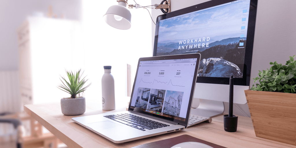 A clean, minimalist desk with a laptop and a motivational AI-related desktop background.
