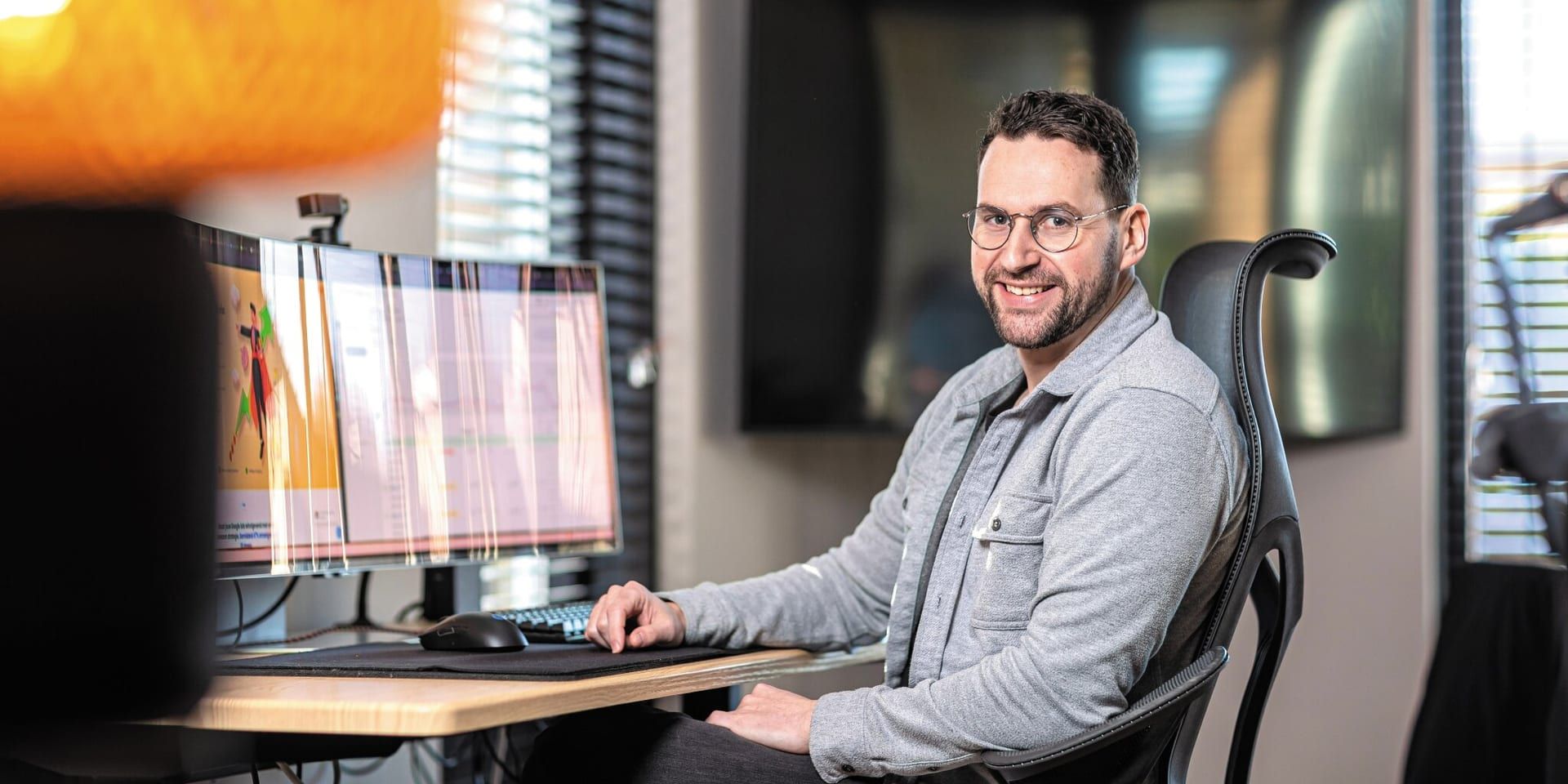 Smiling Ecomtrada founder Lennard Steeman working at dual monitors in an office, illustrating ecommerce Google Ads expertise.