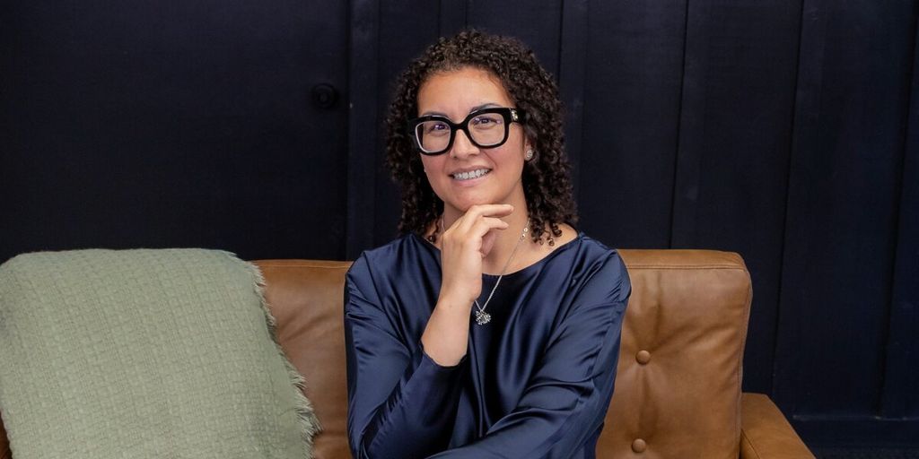 Gina Reyes seated on a sofa, smiling, featured in article about mortgage lending and underwriting expertise.