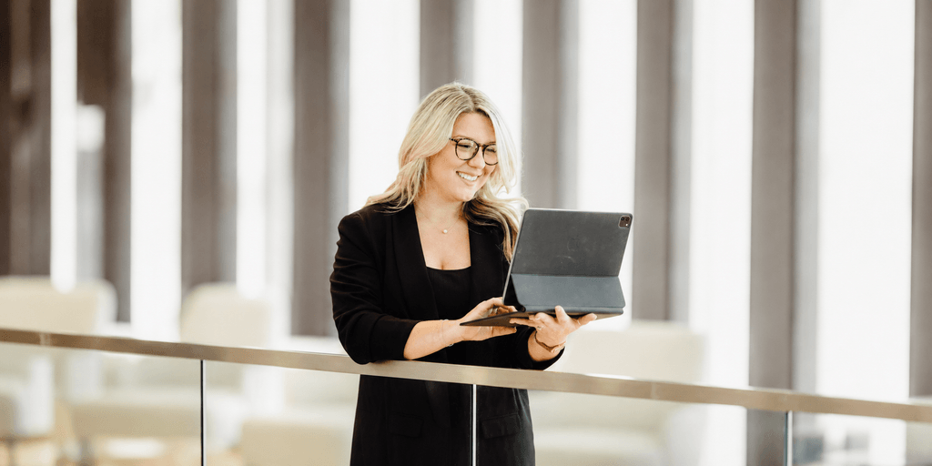 Lauren Foust using a tablet while standing in a modern office workspace.