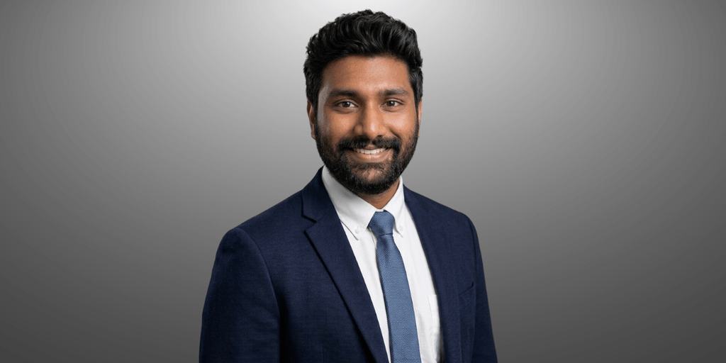 Duvvuru Sravan Kumar Reddy in a gray suit and white shirt against a gray background.