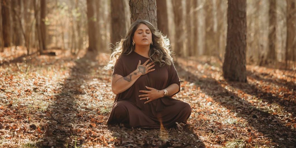 Tiffany Marshall meditating in a forest, embodying the AUM Method™'s Fall phase of release and inner peace.