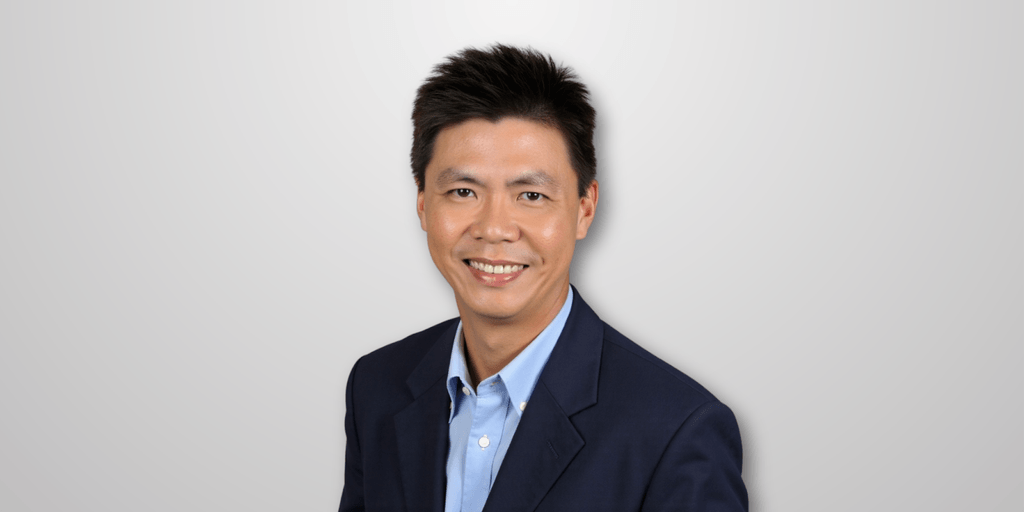 Headshot of a smiling man in a blue blazer, with short hair and a professional demeanor, set against a white background.