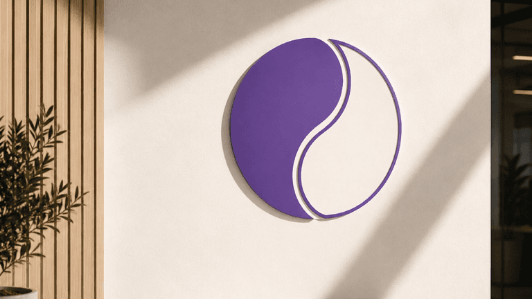 Purple and white circular logo on a textured wall with sunlight casting shadows