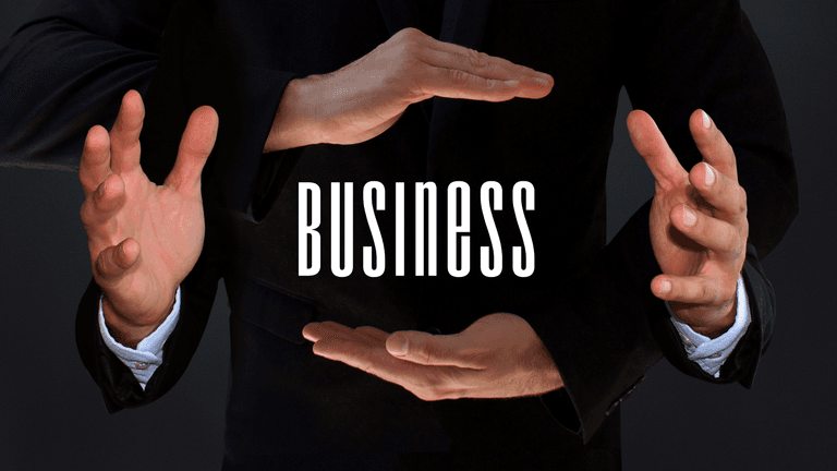 Two hands framing the word "BUSINESS" in a professional setting.