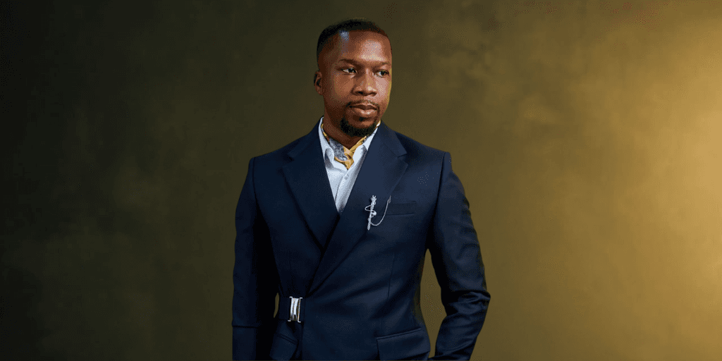 A man in a stylish navy suit stands confidently against a textured background