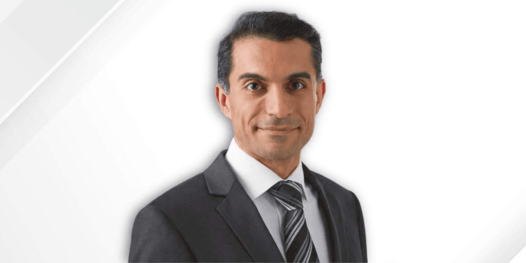 Man in formal suit and tie with a neutral expression against a white background