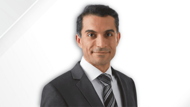 Man in formal suit and tie with a neutral expression against a white background