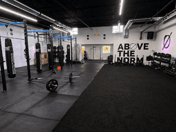 Interior of a gym featuring punching bags, kettlebells, and workout space on black flooring