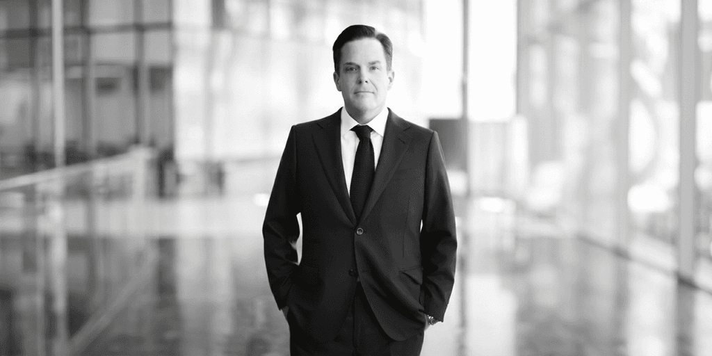 A businessman in a suit stands confidently in a modern, bright interior