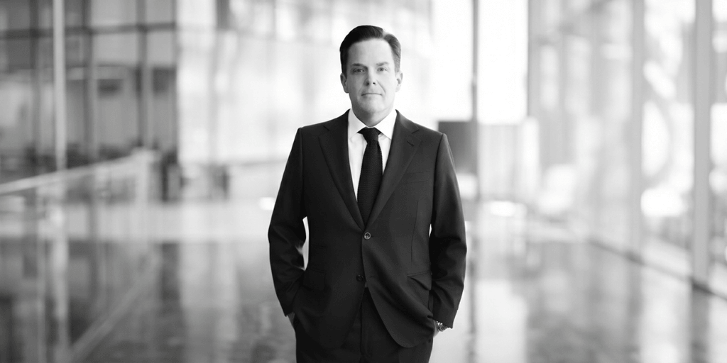 A businessman in a suit stands confidently in a modern, bright interior