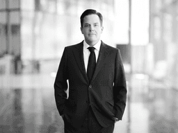 A businessman in a suit stands confidently in a modern, bright interior